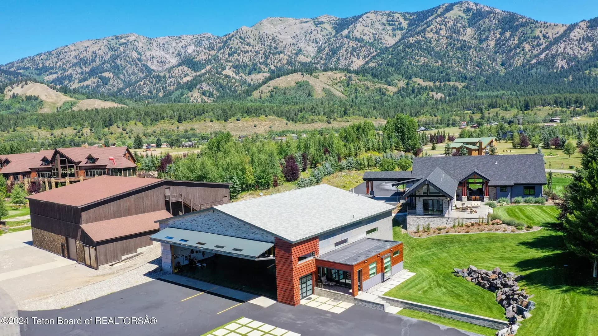 Aerial view of 872 Alpine Village Loop, its detached aircraft hangar, mountain setting, and landscaped grounds